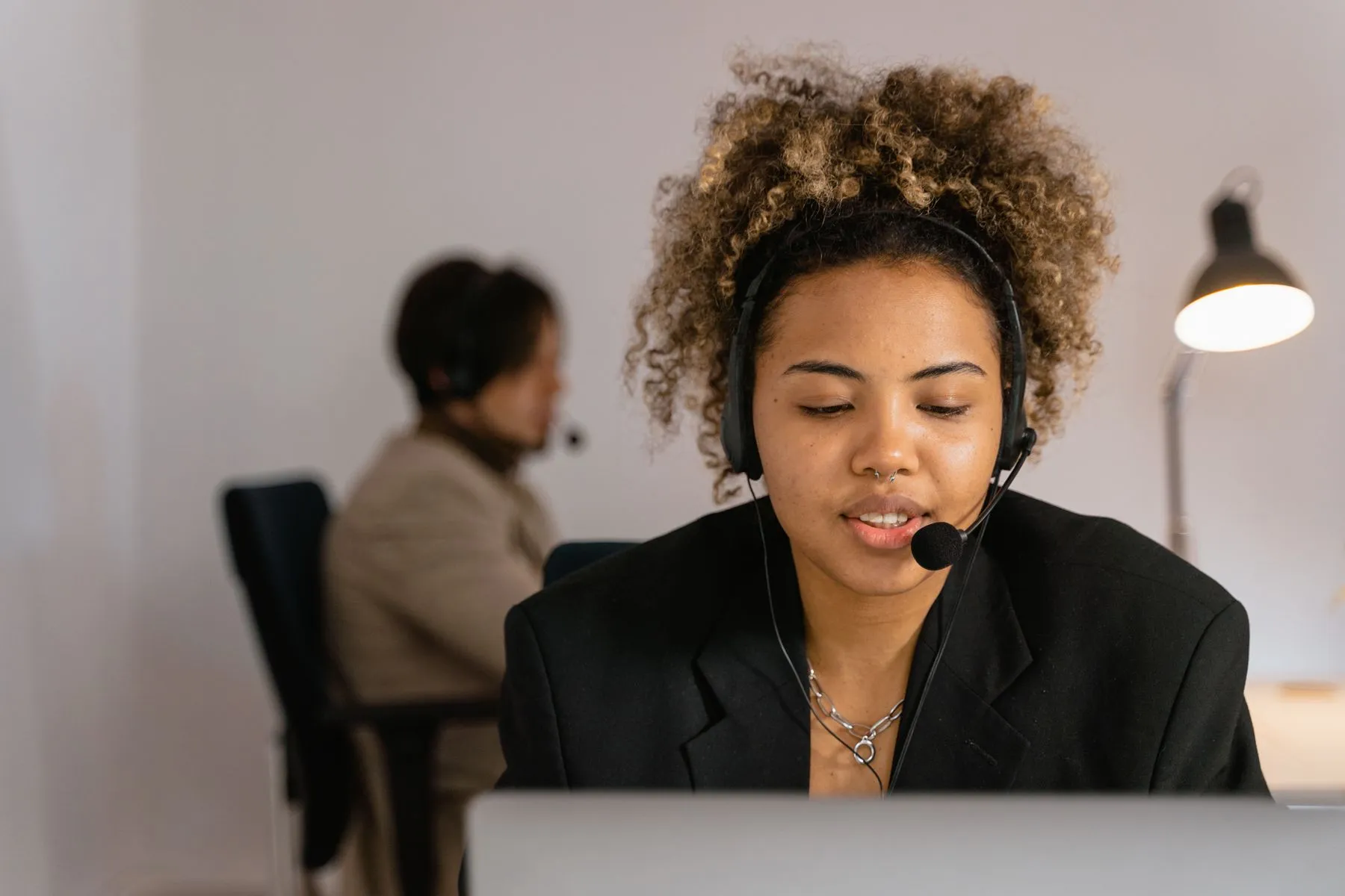 Contact centre agent with a headset talking to a caller at her computer