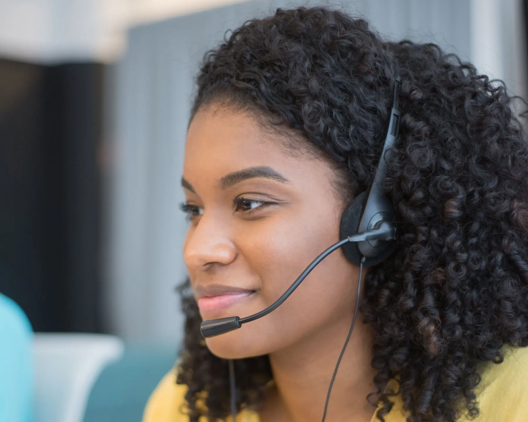 Contact centre agent in a yellow top talking through her headset