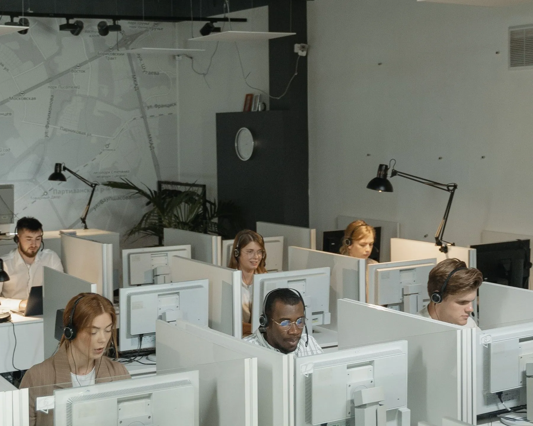 Agents with headsets working at rows of desks in an open plan contact centre