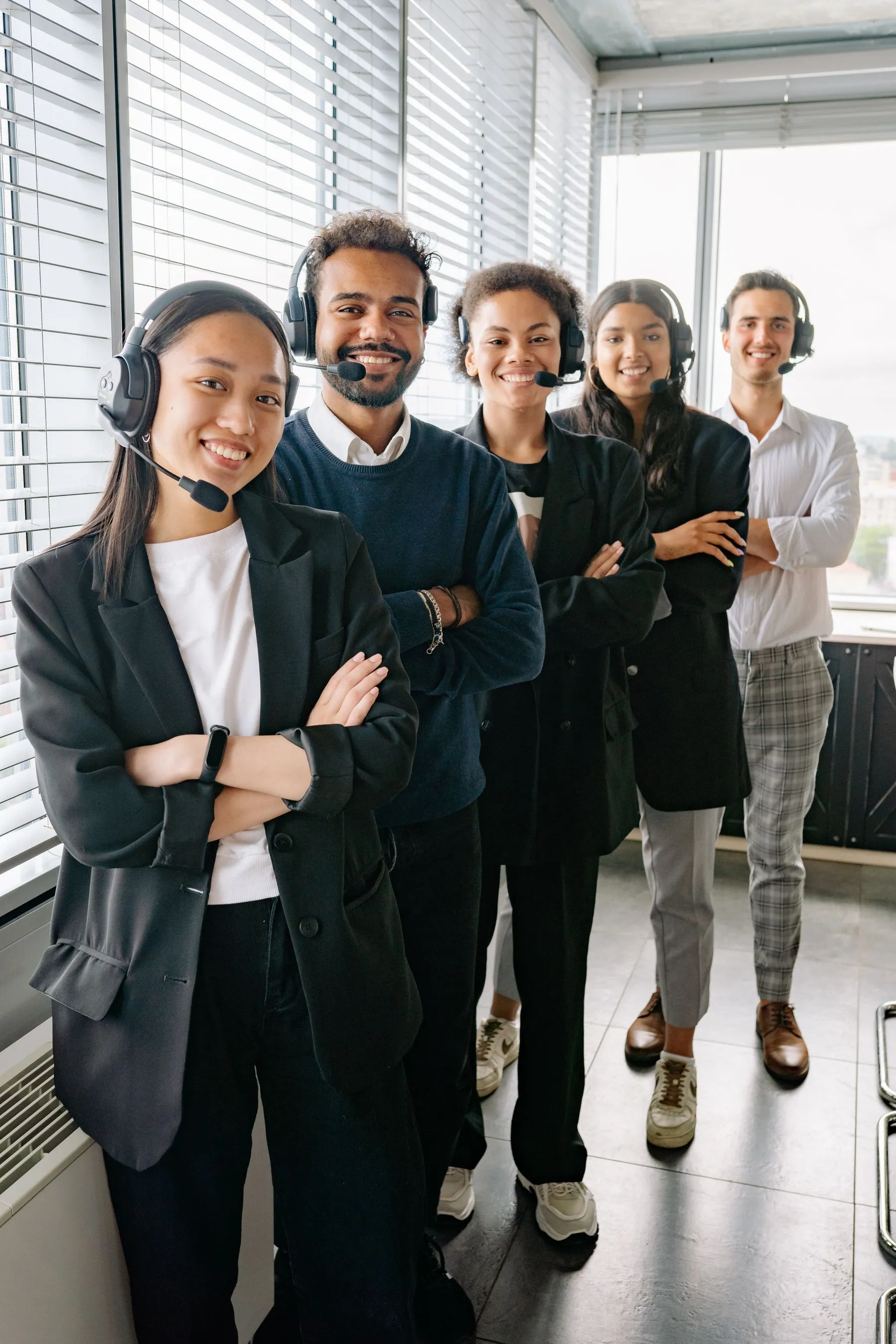 A team of contact centre agents with headsets standing together in an office