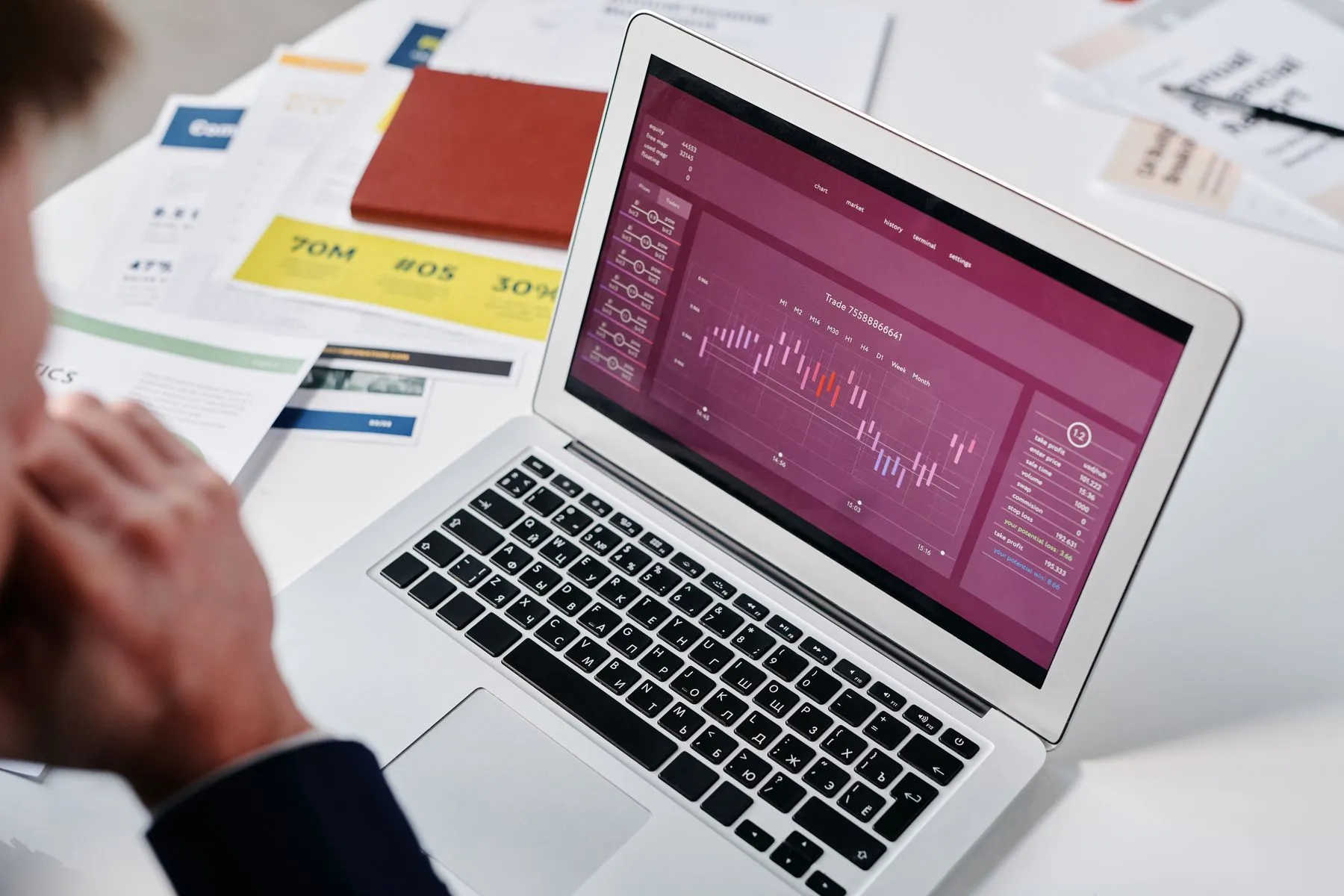 Laptop showing a reporting dashboard with charts, beside printed reports